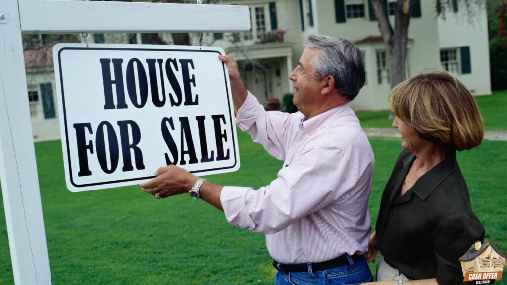 A couple looking at a "house for sale" sign, with the man holding the sign and a house in the background - We Buy Houses in Bedford TX